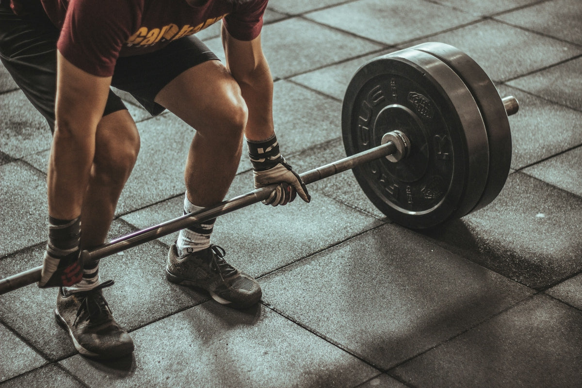 A person lifting a heavy barbell from a rubber gym floor