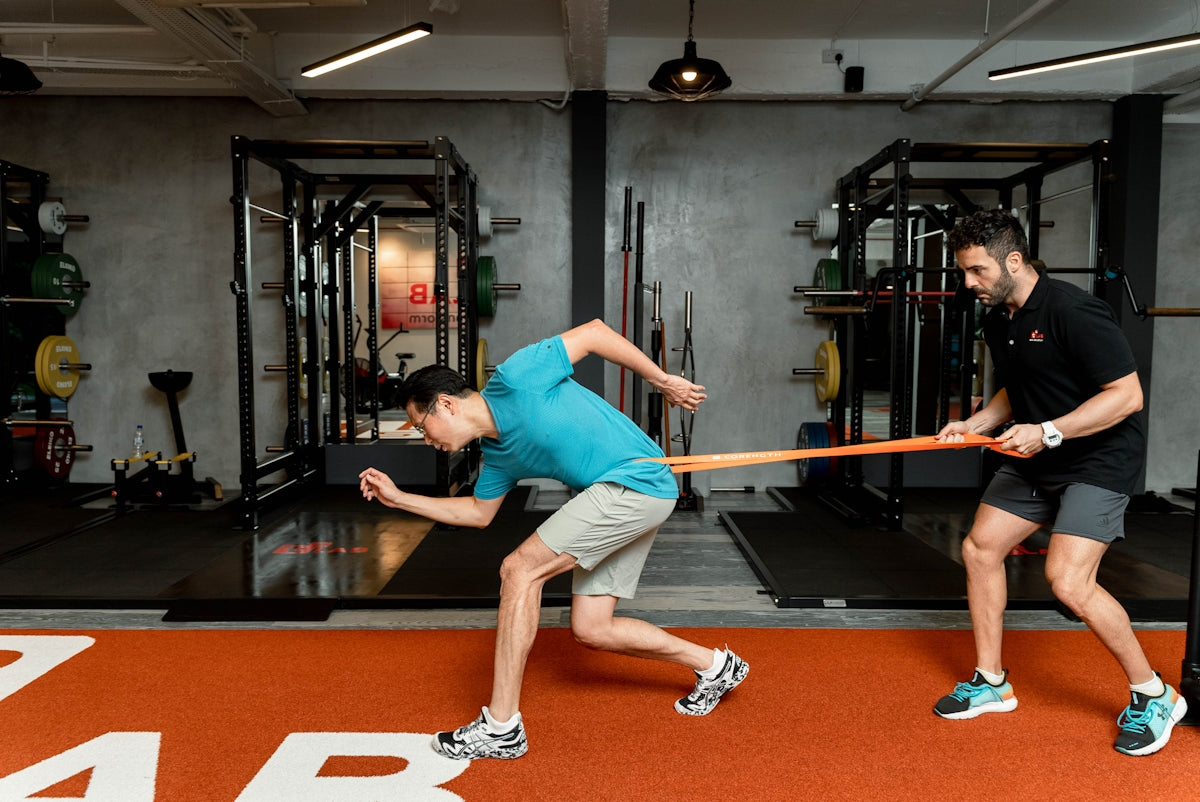 Man resists resistance band during athletic training exercise.