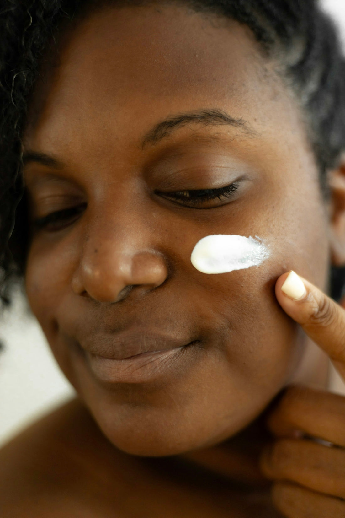 a woman is putting a lotion on her face