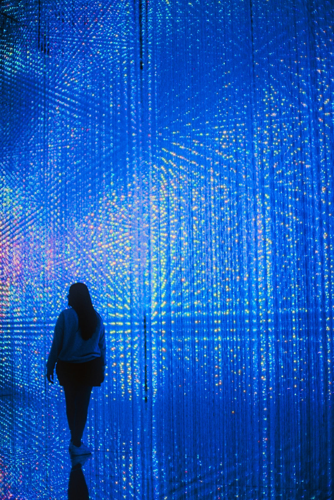 A person walking in front of a blue wall